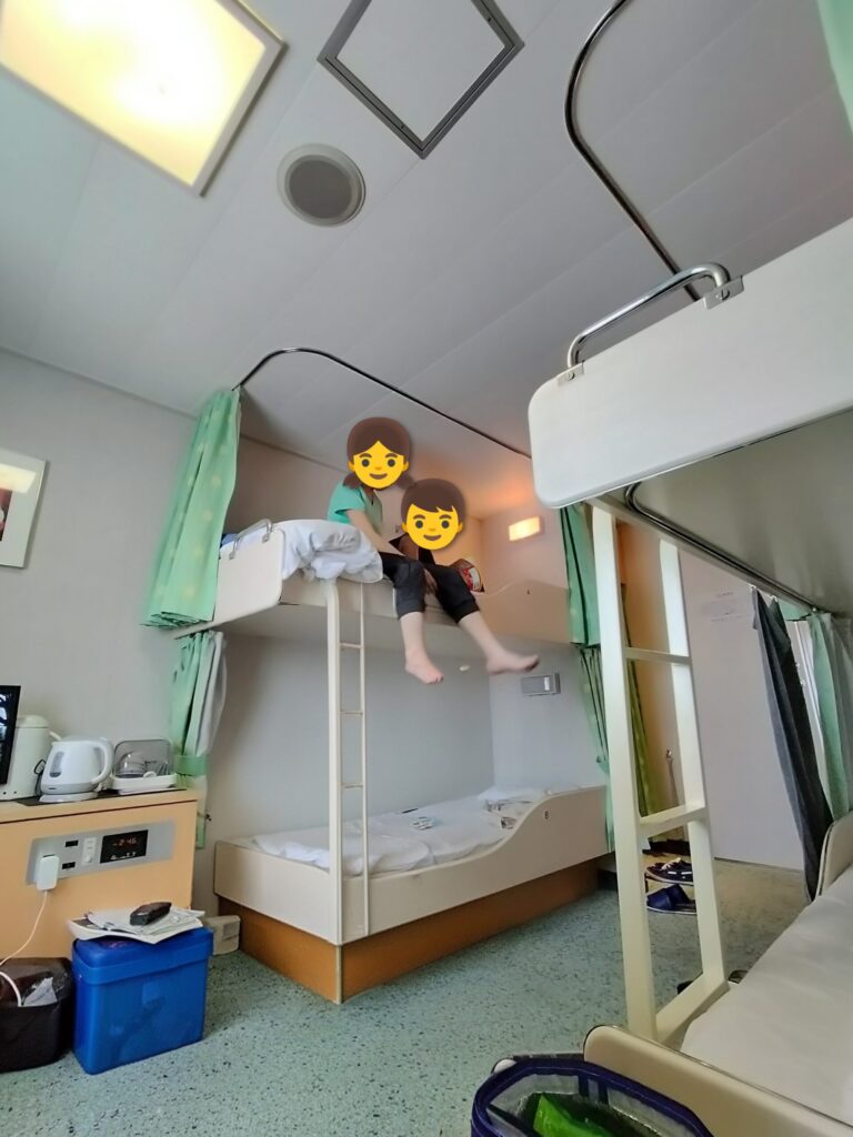 個室の2段ベッド上段で子供たちが遊んでいる様子